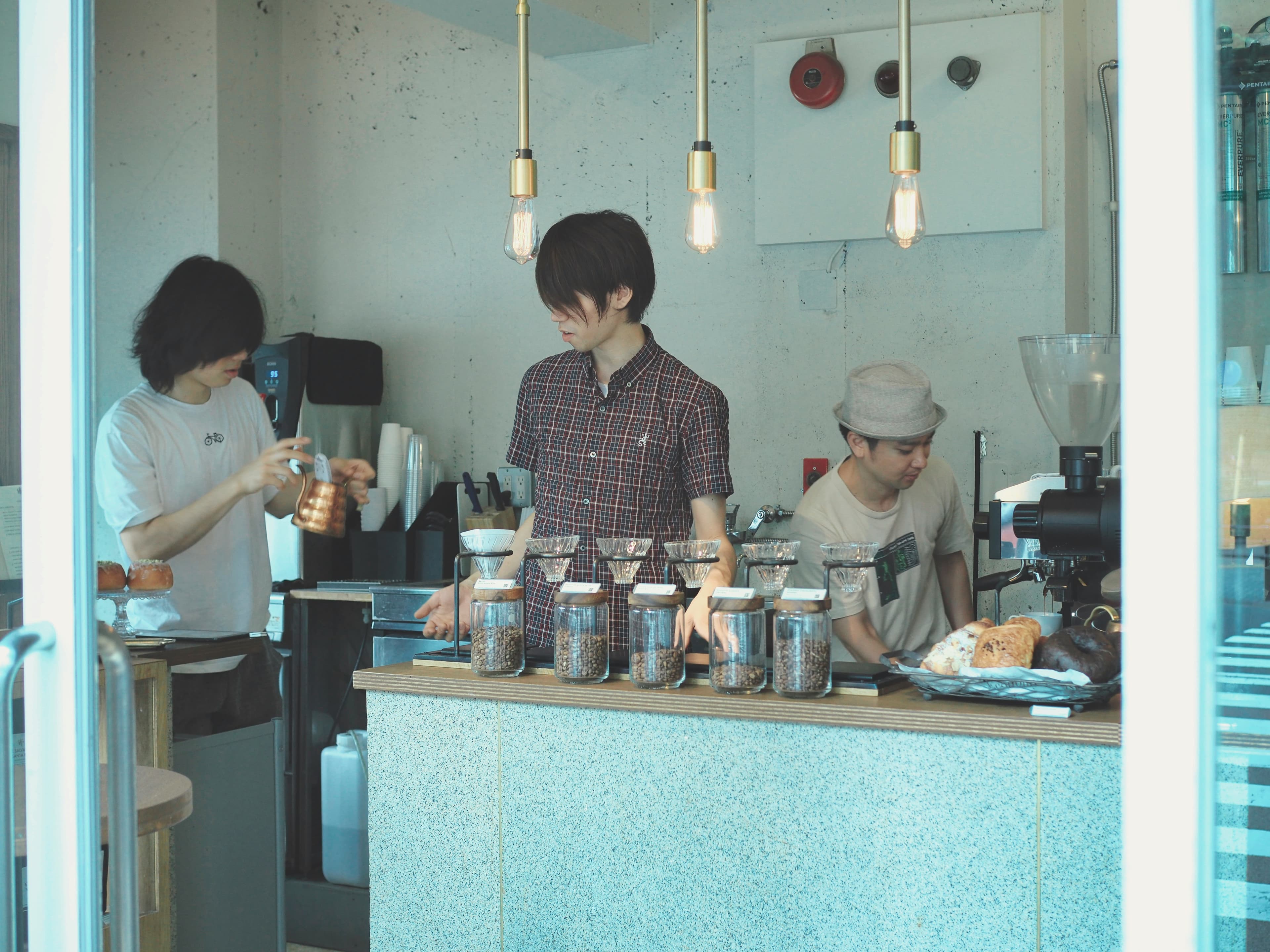 Three baristas preparing pour-over coffee behind the counter