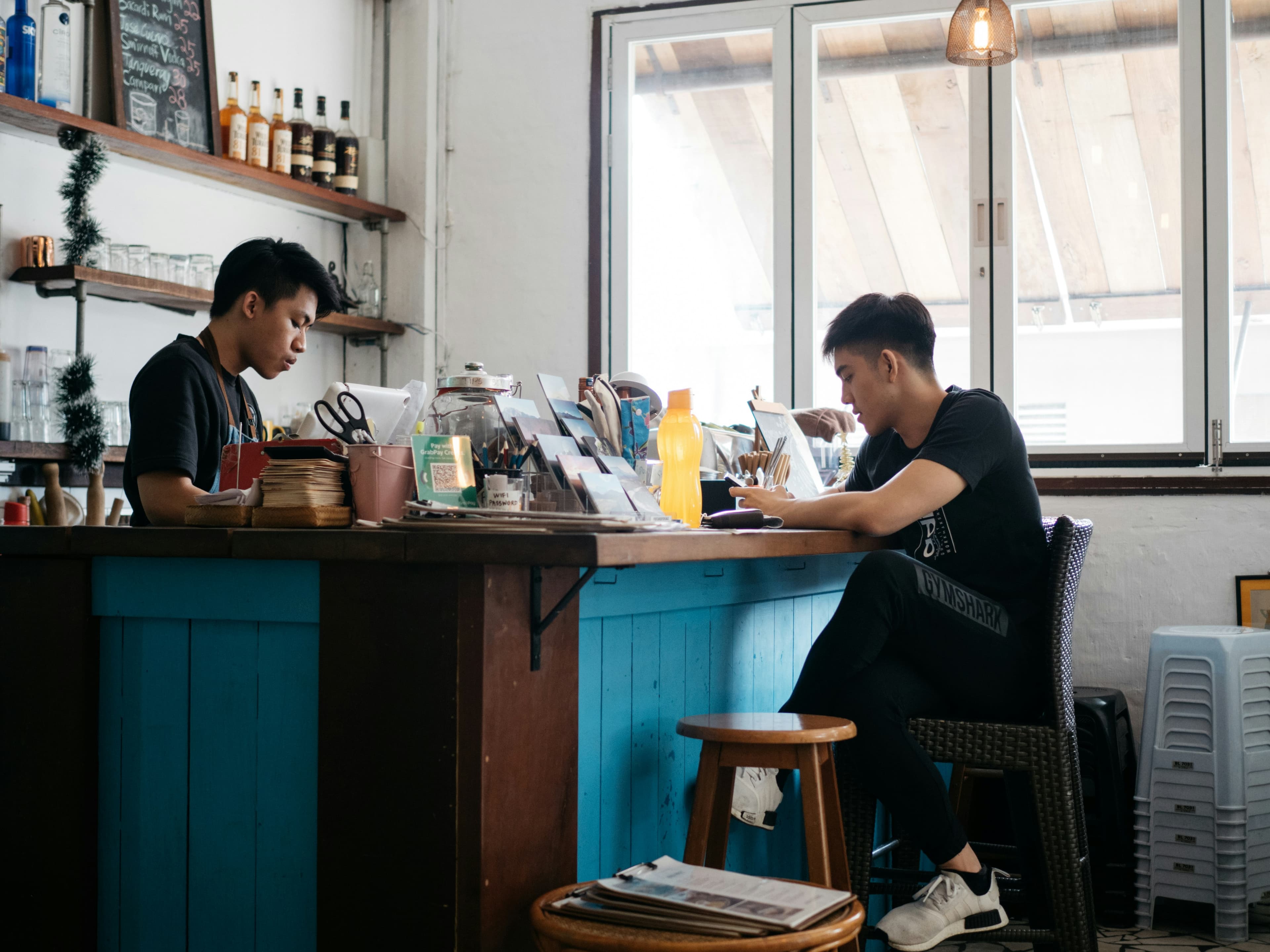 Barista and a guest at the wooden bar of Baan Kaffe